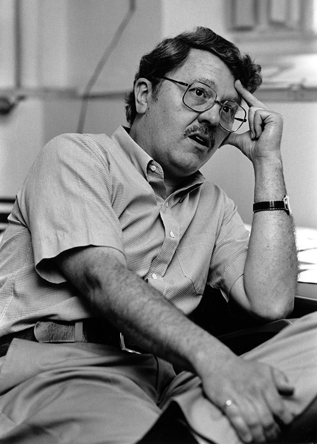A black and white photograph of former Oberlin professor David Young sitting with his hand on his head in thought.